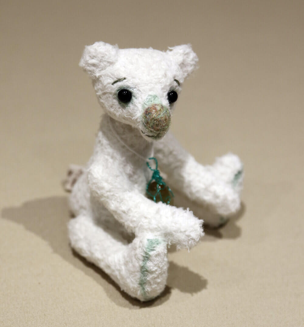 Pistachio by Brierley Bears. Handmade white artisan bear shown sitting, right side. Made from white viscose with green detailing.
