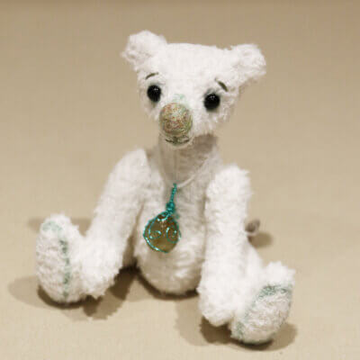 Pistachio - handmade white artisan bear made from white viscose with green details. Sitting.